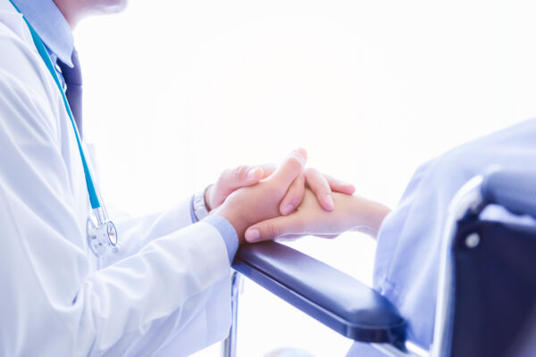 患者と医者が手を取り合う手元写真